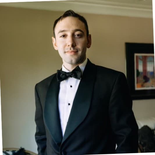 A man in a black tuxedo with a shawl lapel, white shirt, and black bow tie.
